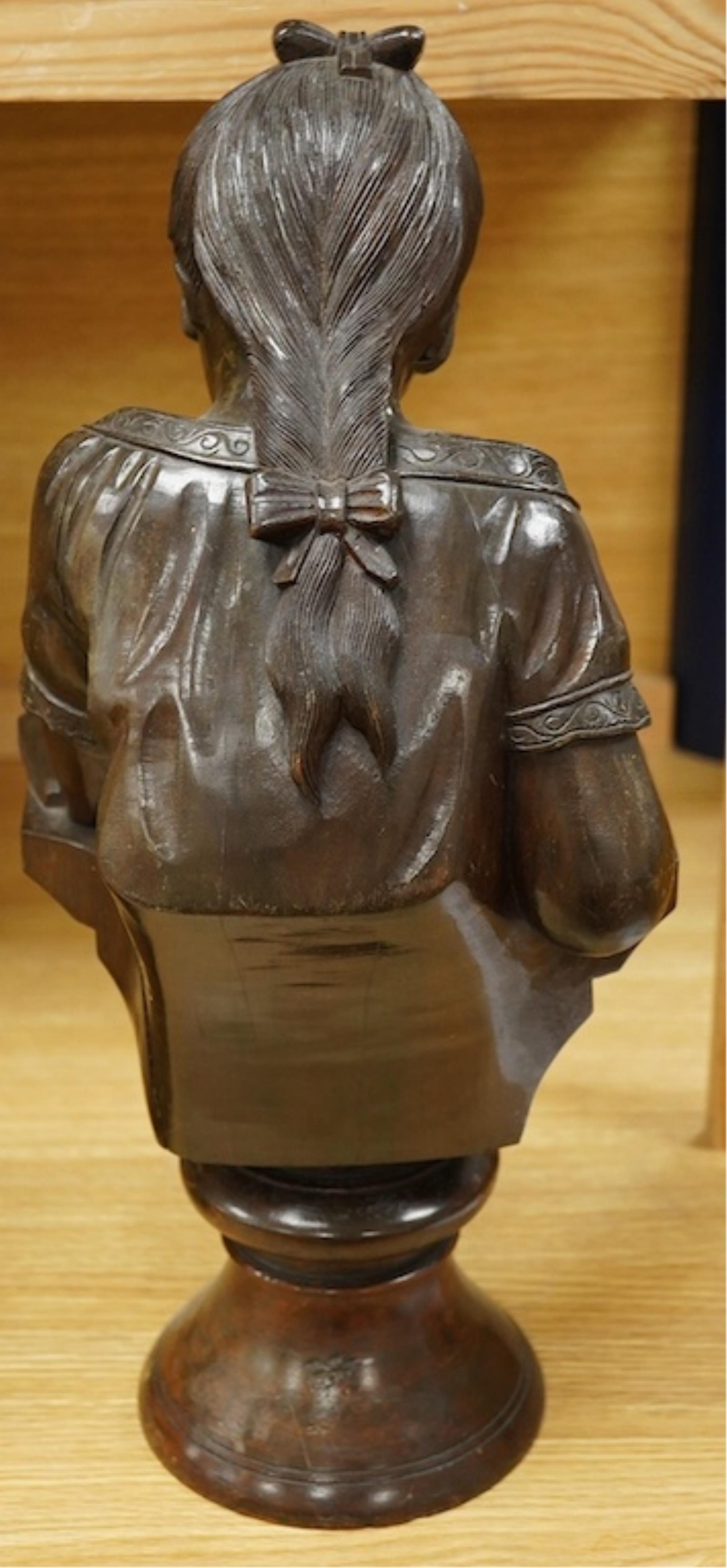 A carved wood bust of a girl sewing, 47cm high. Condition - two old cracks to the back of carving